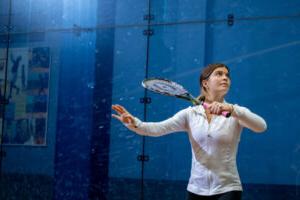 Trinity college squash player serving the ball with racket